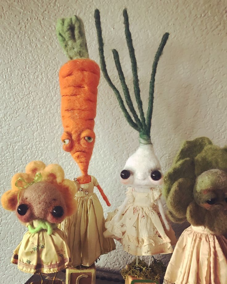 three stuffed animals are standing next to each other on a shelf with carrots in the background