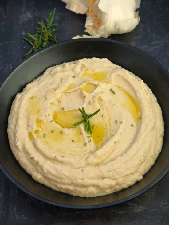 hummus in a black bowl with garlic and herbs