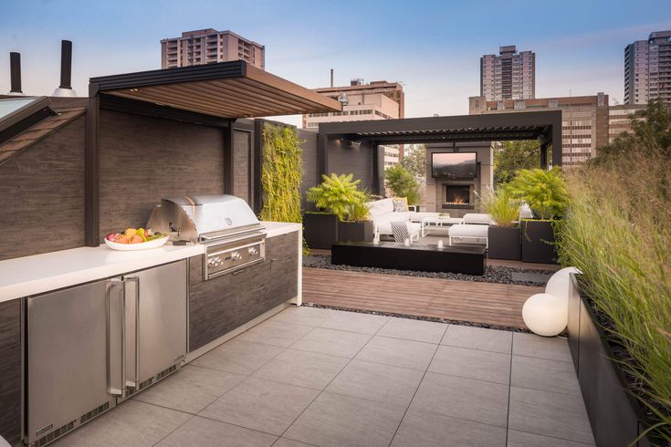 an outdoor kitchen with stainless steel appliances and grilling area in the foreground, surrounded by high rise buildings