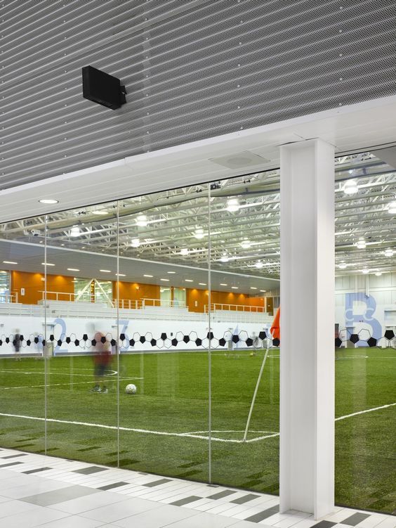 an indoor soccer field is reflected in the glass walls