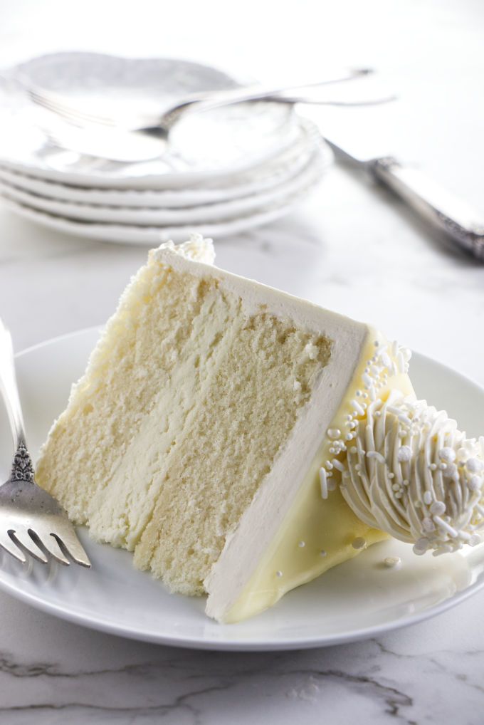 a piece of white cake on a plate with fork and knife next to the slice