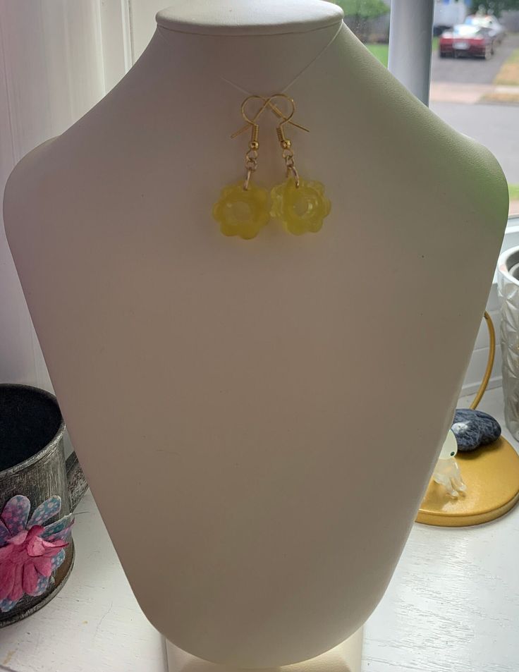 Resin flower shape dangle earrings. These are yellow resin. Hook is gold tone. Very light fun earrings. Please note that with working with resin, bubbles can and may happen. each piece is handmade and unique. Gold Resin Jewelry With Ear Wire, Gold Flower Resin Earrings, Resin Flower Charm Drop Earrings, Resin Drop Earrings With Flower Charm, Resin Dangle Flower Earrings With Flower Charm, Resin Flower Charm Dangle Earrings, Resin Dangle Flower Earrings With Ear Wire, Dangle Resin Flower Charm Earrings, Handmade Resin Flower Shaped Earrings