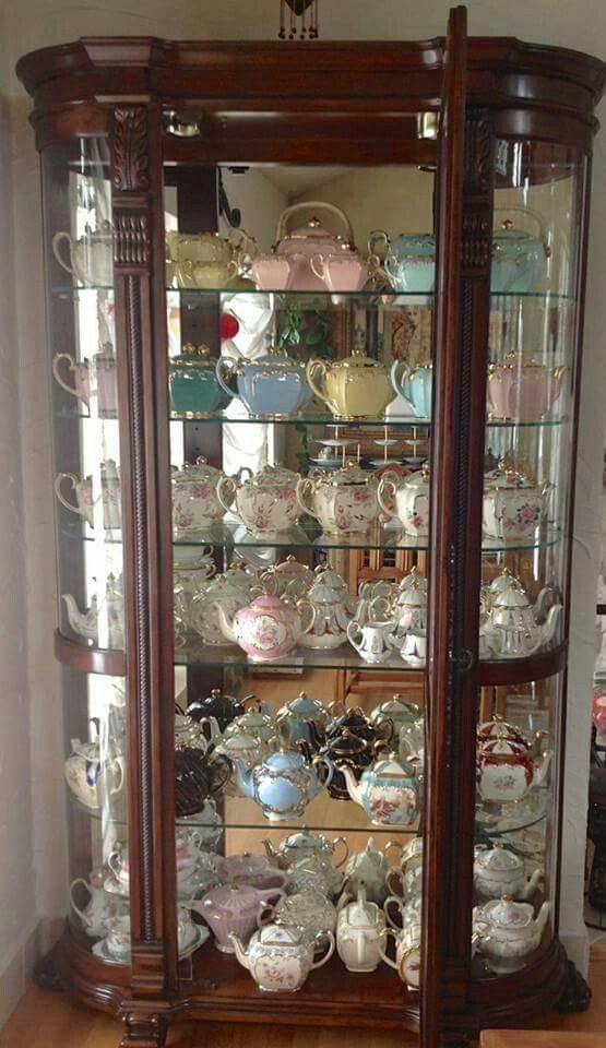 a china cabinet with glass doors and lots of teacups on it's shelves