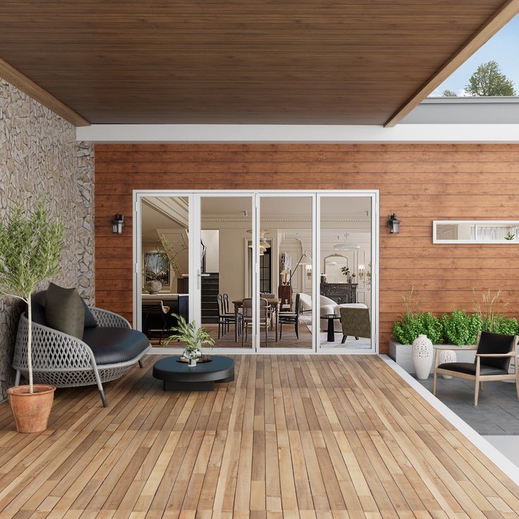 a wooden deck with chairs and potted plants next to the sliding glass door that leads to an outdoor living area