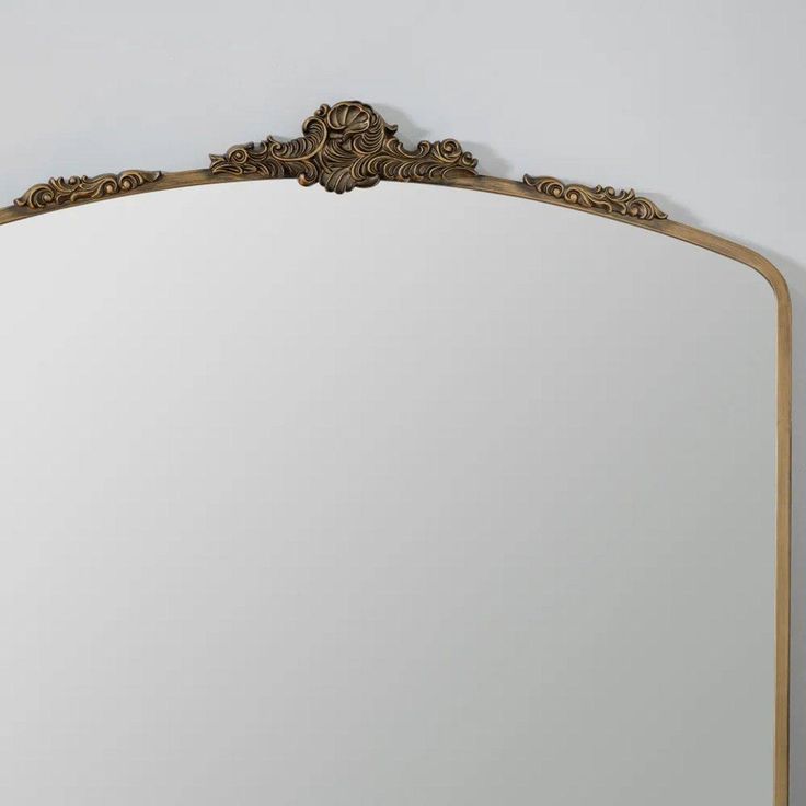 an ornate gold framed mirror against a white wall