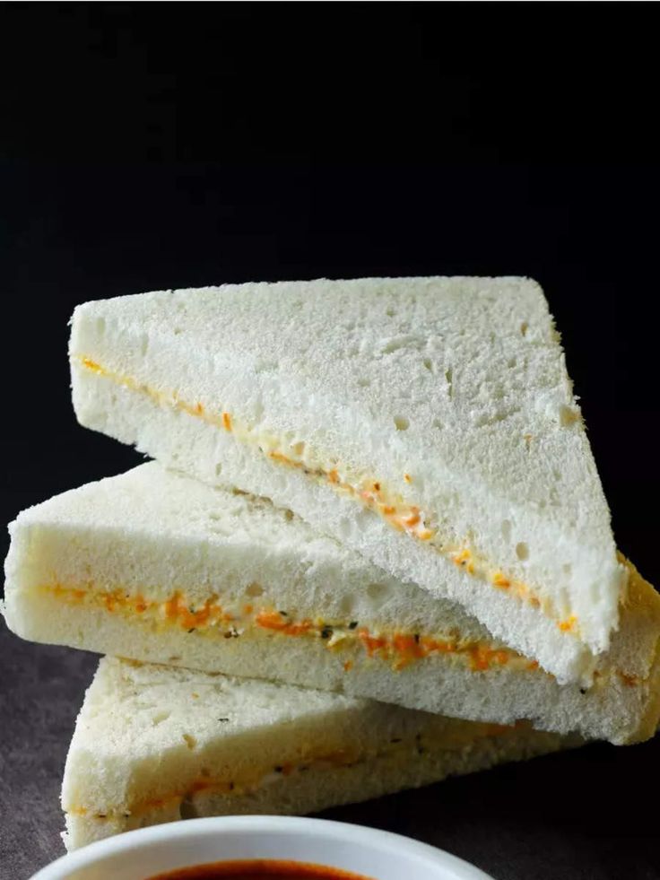 two sandwiches cut in half sitting next to a bowl of dipping sauce on a table