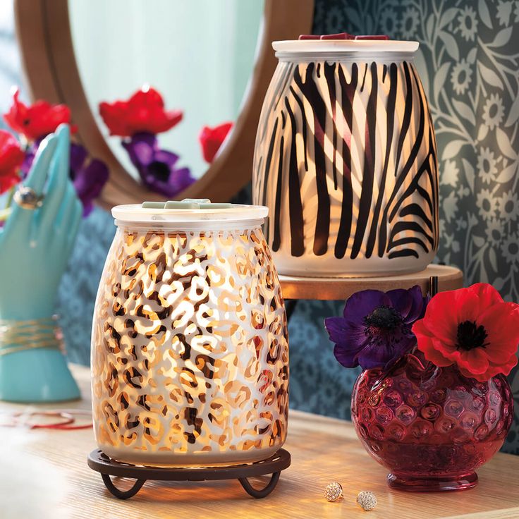 two vases with flowers on a table next to each other and a mirror in the background