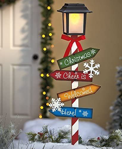 a christmas street sign with snowflakes on it and a lit candle in the background