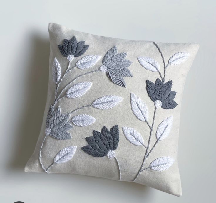 a white pillow with grey leaves on it