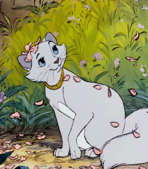 the white cat is sitting on the ground in front of some flowers and grass with pink petals