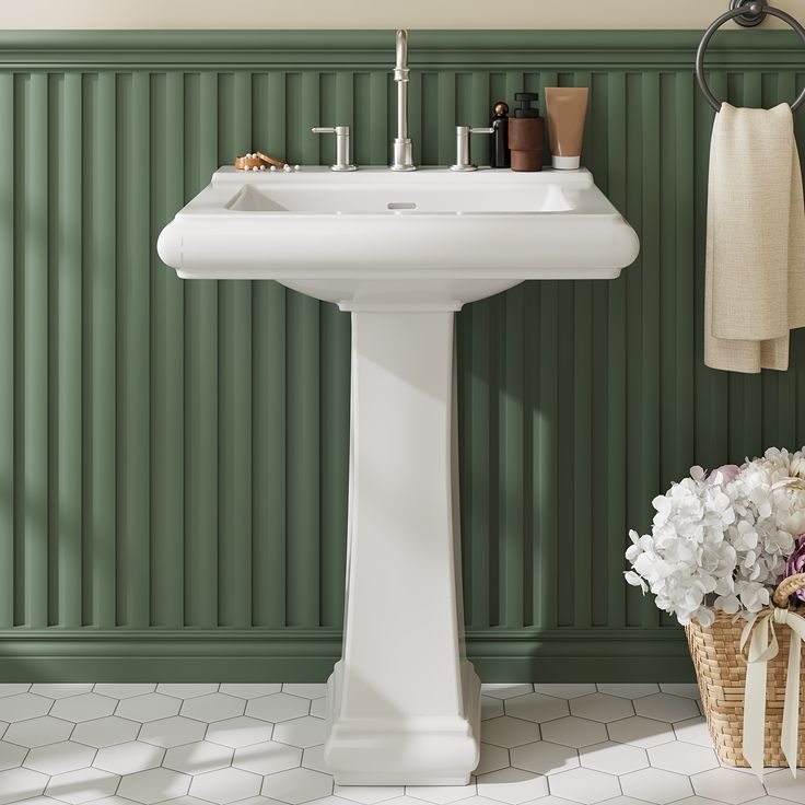 a white pedestal sink sitting next to a green wall