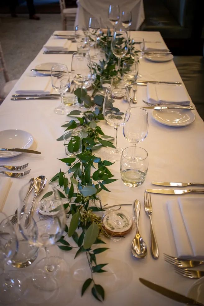 a long table is set with silverware and greenery for an elegant wedding reception