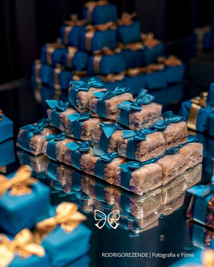 many blue boxes with gold bows are stacked on top of each other