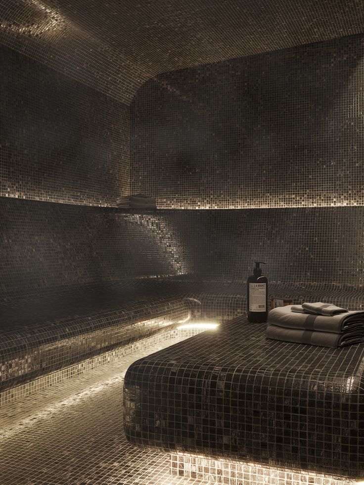 a dimly lit room with black and white mosaic tiles on the walls, along with a bed