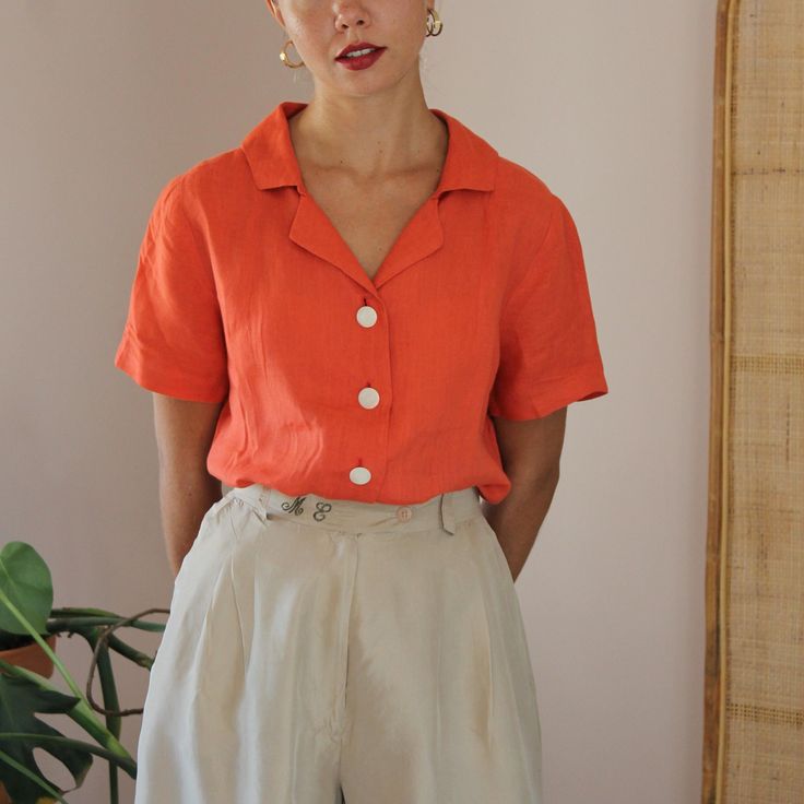 Delicate vintage blouse in a beautiful deep earthy orange colour. Handmade with a stunning contrast cream button up fastening. Collared with short sleeves. 100% linen. Lightweight with a boxy fit. Extra soft, and comfortable, it is ideal for your everyday summer looks! ** Vintage silk shorts available here >> https://www.etsy.com/listing/1740790692/vintage-silk-shorts-in-light-beige MATERIAL: No tag, known to be 100% linen BRAND: Handmade **CONDITION: Excellent Vintage Condition **MEASUREMENTS: Classic Orange Short Sleeve Shirt, Classic Orange Summer Shirt, Chic Orange Collared Top, Summer Blouse With Button Cuffs And Lapel Collar, Orange Short Sleeve Shirt With Buttons, Orange Collared Summer Blouse, Classic Summer Blouse With Covered Buttons, Vintage Orange Blouse For Summer, Orange Tops With Spread Collar For Spring