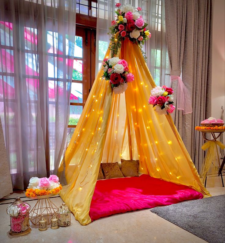 a yellow tent with pink and white flowers on it sitting in front of a window