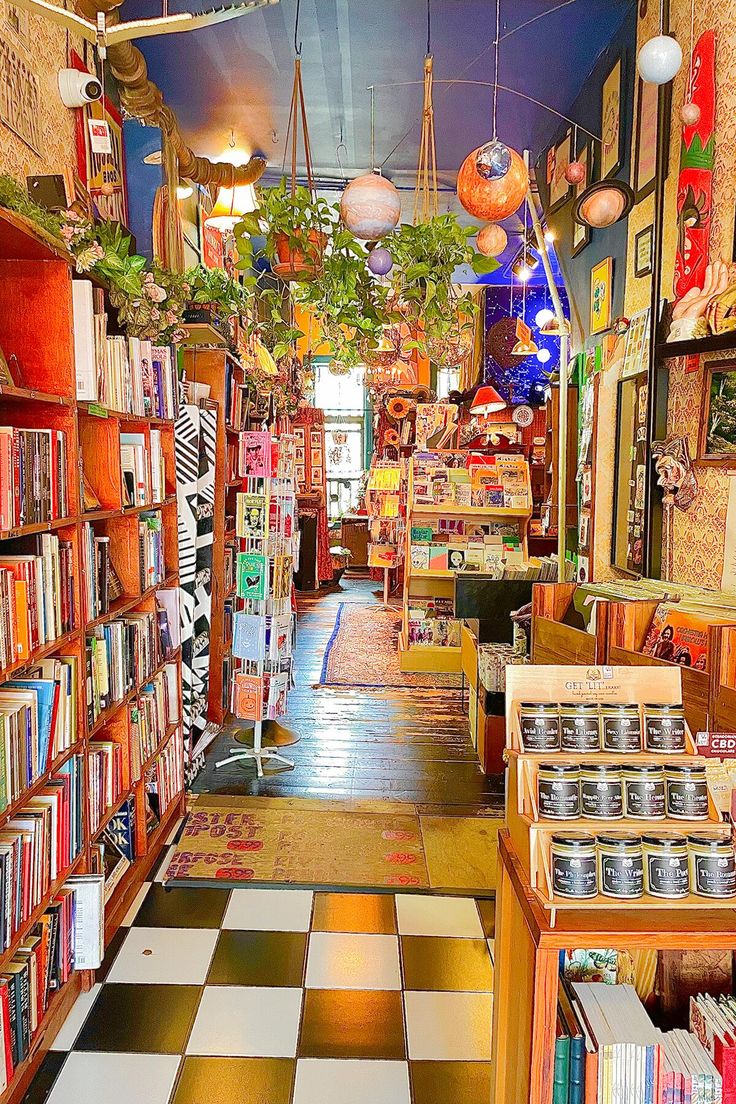 the inside of a book store filled with lots of books on shelves and lamps hanging from the ceiling