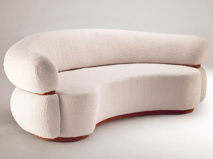 the curved couch is white and has a wooden frame on it's back end