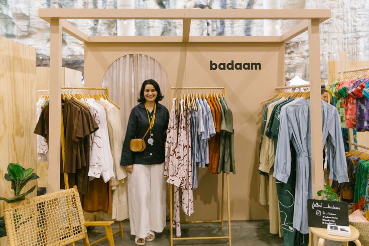 a woman standing in front of a rack with clothes on display at a clothing store