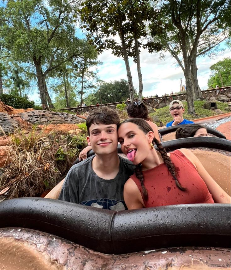 two people are riding in an elephant ride at the zoo with trees and rocks behind them