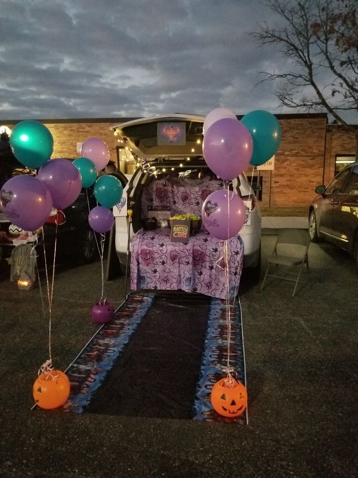 the trunk of a van is decorated with purple, green and blue balloons for halloween