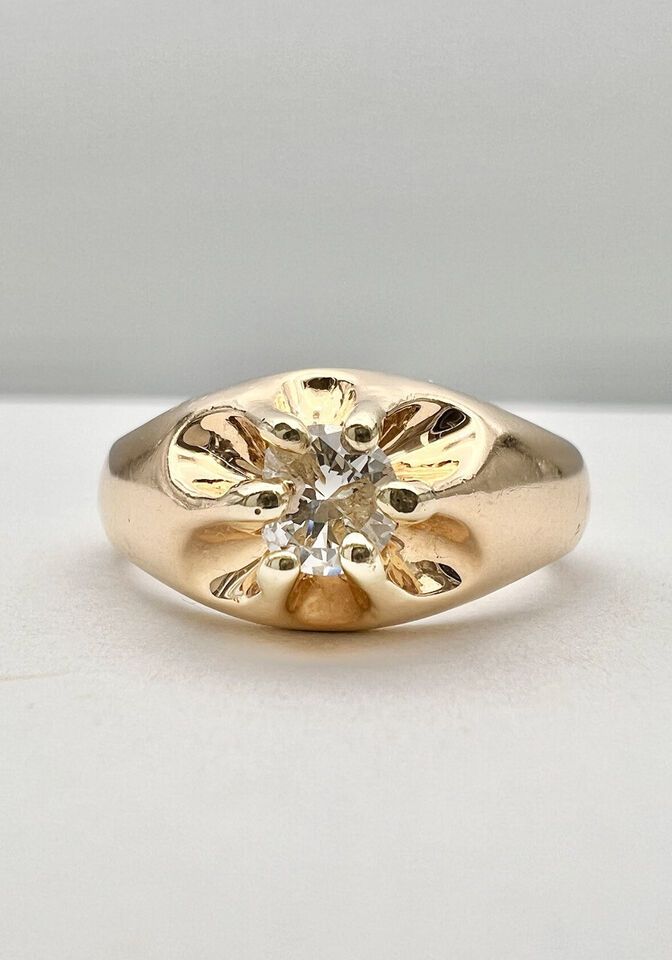 a yellow gold ring with a single diamond in the center, on a white surface