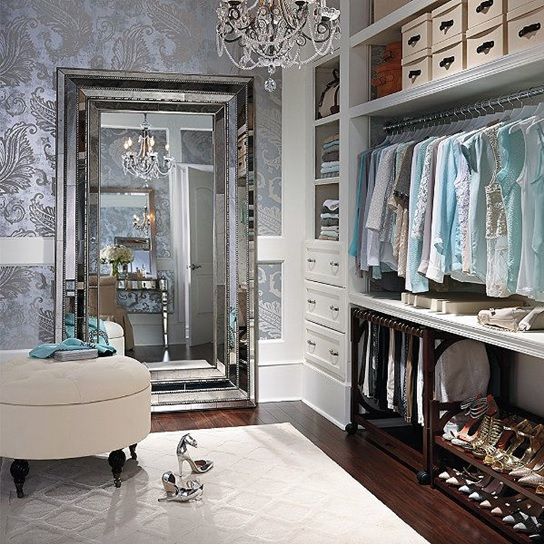 a walk in closet with lots of clothes on hangers next to a chandelier