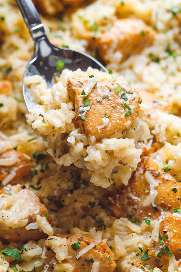 a spoon full of rice with shrimp and parsley on it, being lifted from the casserole