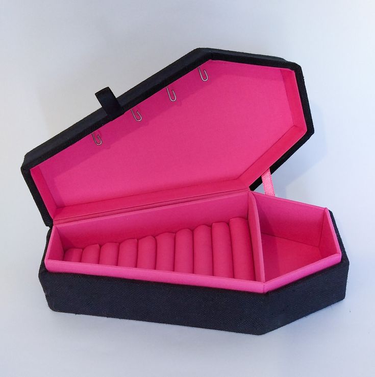 an open black and pink box with six candles inside on a white tablecloth background