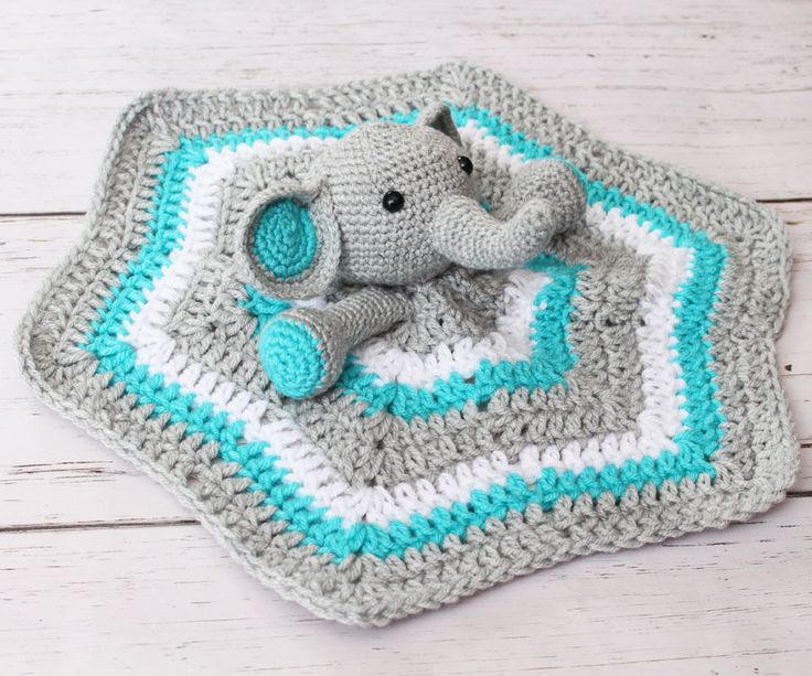 an elephant crocheted blanket on top of a white wooden floor next to a stuffed animal