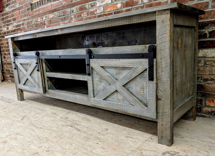 an old wooden entertainment center with sliding doors on the front and side, against a brick wall