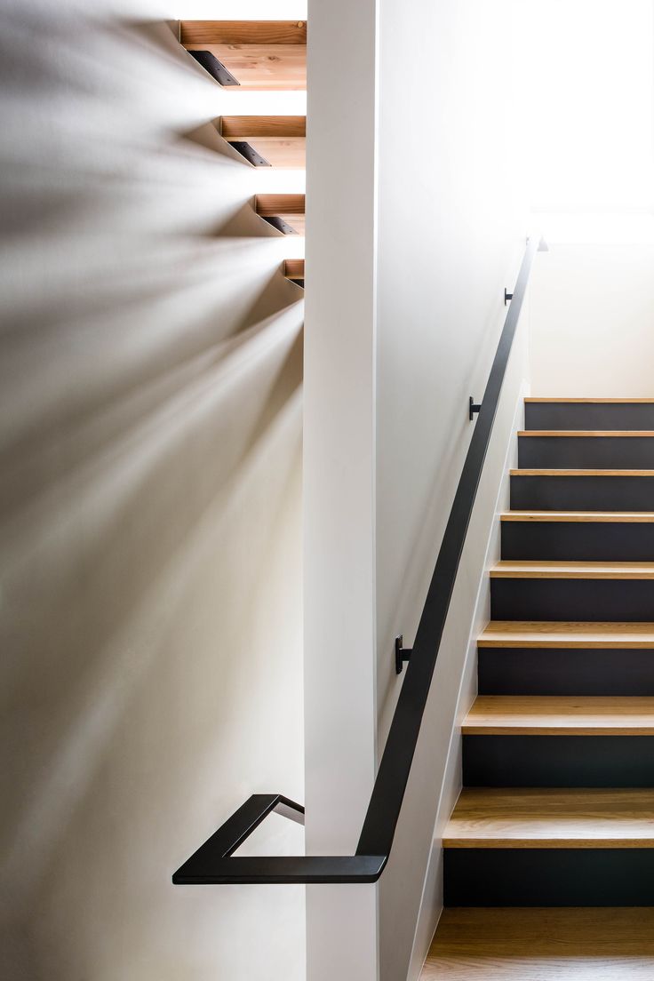 the light shines through the window above the stairs in this modern house with wood and white walls