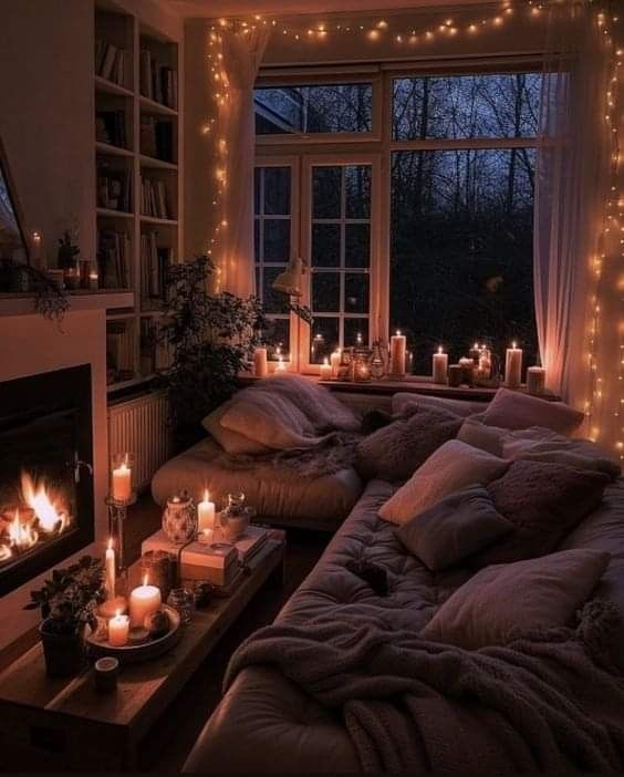 a living room filled with lots of candles next to a window covered in blankets and blankets