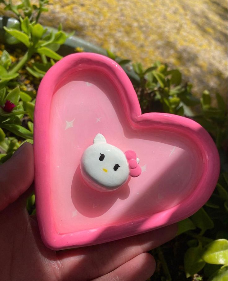 a pink heart shaped object with a hello kitty face on it