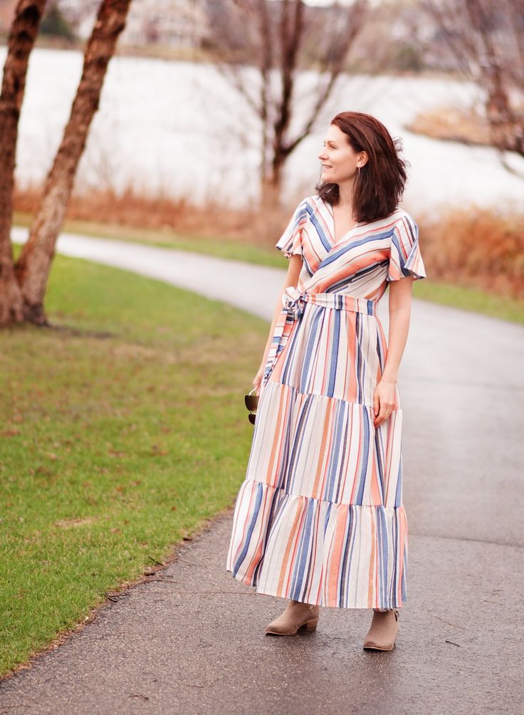 a woman in a striped dress is walking down the street