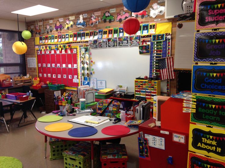 an empty classroom with many different colored bins on the wall and colorful decorations hanging from the ceiling