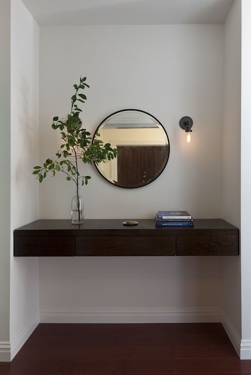 a mirror on the wall above a shelf with a potted plant