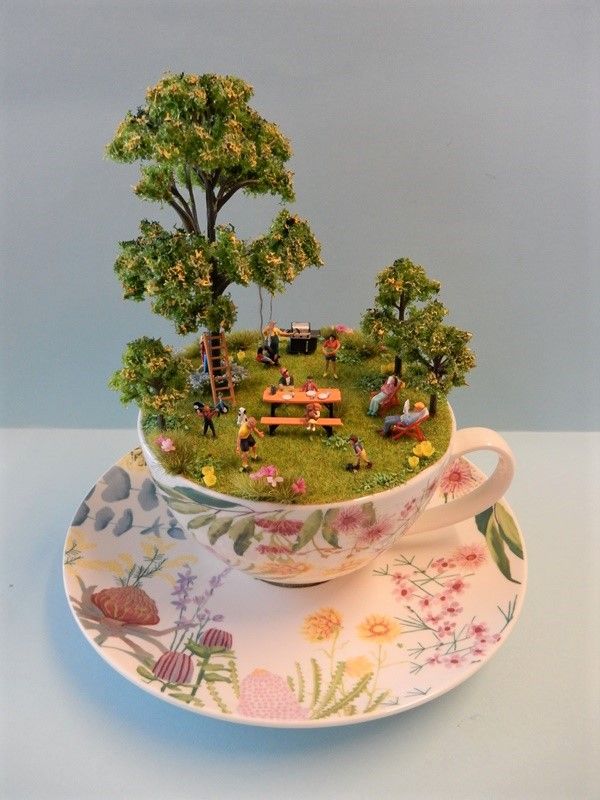 a teacup with a miniature garden in it sitting on a saucer next to a plate