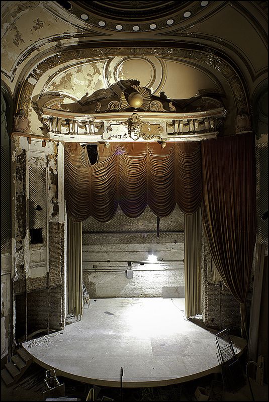 black and white photograph of an empty stage with curtained area in the center,