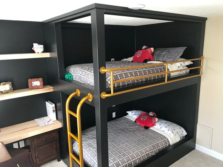 a bunk bed with two sets of beds underneath it in a room that has black walls and carpet