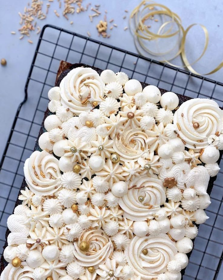 a chocolate cake with white frosting and seashells on top is sitting on a cooling rack