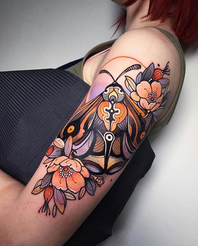 a woman's arm with an owl and flowers tattoo on it