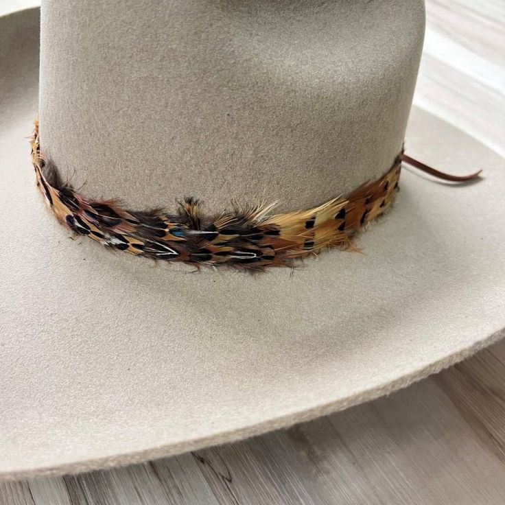 Natural feather hat band. Adjustable with a leather tie. Natural colored feathers Adjustable hatband Approx. 1 inch wide *This product is for 1 single hat band. Hat not included. Adjustable Hat Bands For Country Events In Fall, Adjustable Country Hat Bands For Fall, Adjustable Brown Hats For Hunting, Rustic Adjustable Hat For Hunting, Adjustable Felt Hat With Curved Brim For Hunting, Adjustable Felt Hunting Hat With Curved Brim, Adjustable Top Hat For Country Events In Fall, Adjustable Hat Band For Rodeo In Winter, Rustic Adjustable Brown Top Hat