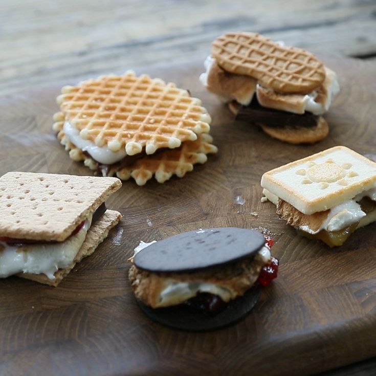 four waffle sandwiches on a cutting board with cheese and jelly in the middle one is cut in half