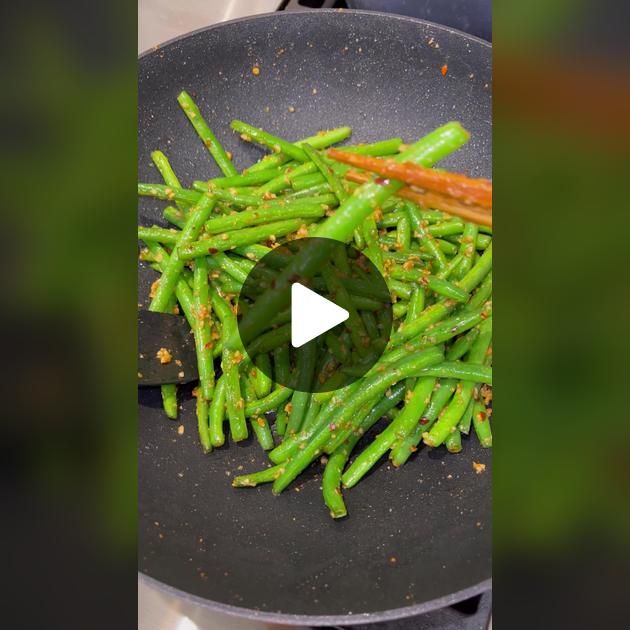 green beans being cooked in a frying pan on the stove with a video playing