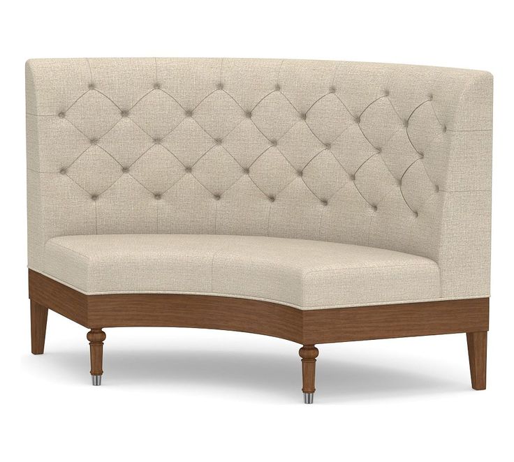 a beige couch with wooden legs and buttons