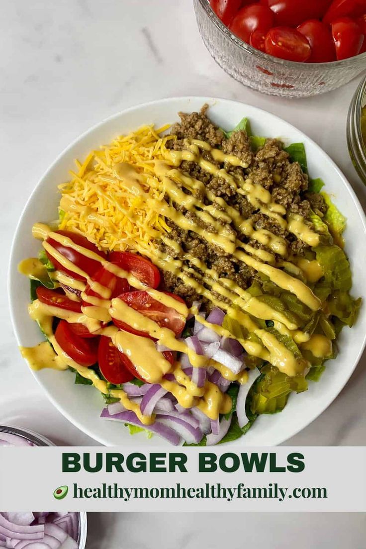 a white plate topped with salad covered in cheese and dressing next to some sliced tomatoes