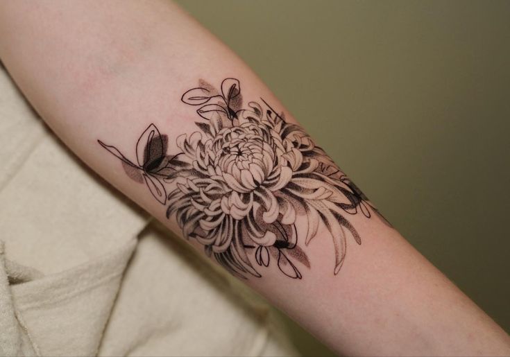 a black and white flower tattoo on the arm