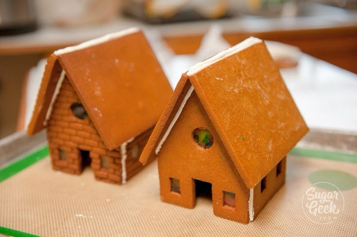 two small houses made out of clay sitting on a cutting board with green trim around the edges