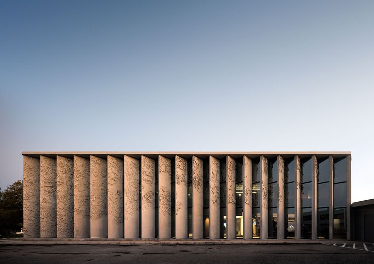 an empty parking lot in front of a building with columns on the sides and windows